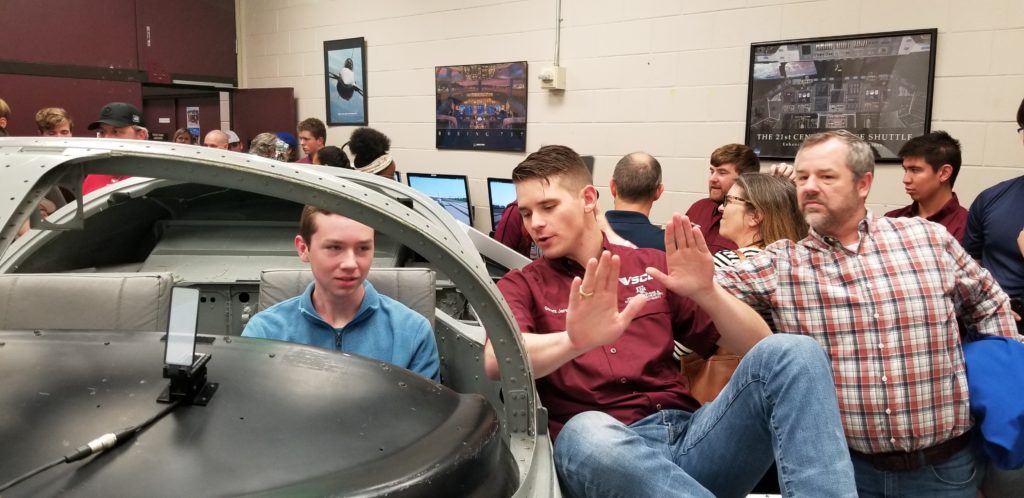 PhD student Garrett Jares explains rudder controls to visiting high school student